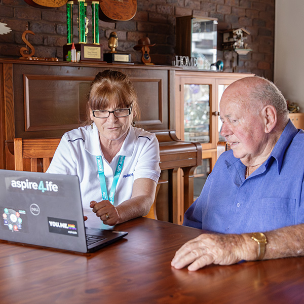 Photo of Aspire4Life Assessor show client something on laptop